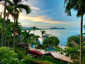 Un resort con piscina, palmeras y vista al mar.