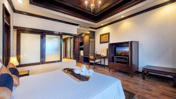 A hotel room with a large bed, a desk, a television, and a bench.