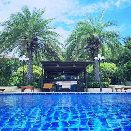 Una piscina al aire libre, sombrillas, sillones reclinables de piscina