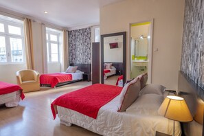 Une chambre d’hôtel avec deux lits, une chaise, un miroir et une lampe.