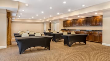A conference room with a carpeted floor, round tables, and chairs.