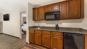 Una cocina compacta con armarios de madera, microondas integrado y lavavajillas.
