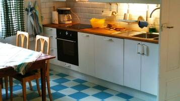 A kitchen with white cabinets, a checkered floor, a coffee maker, and a sink.