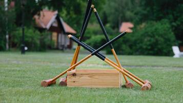A wooden box with four croquet mallets on a grassy field.