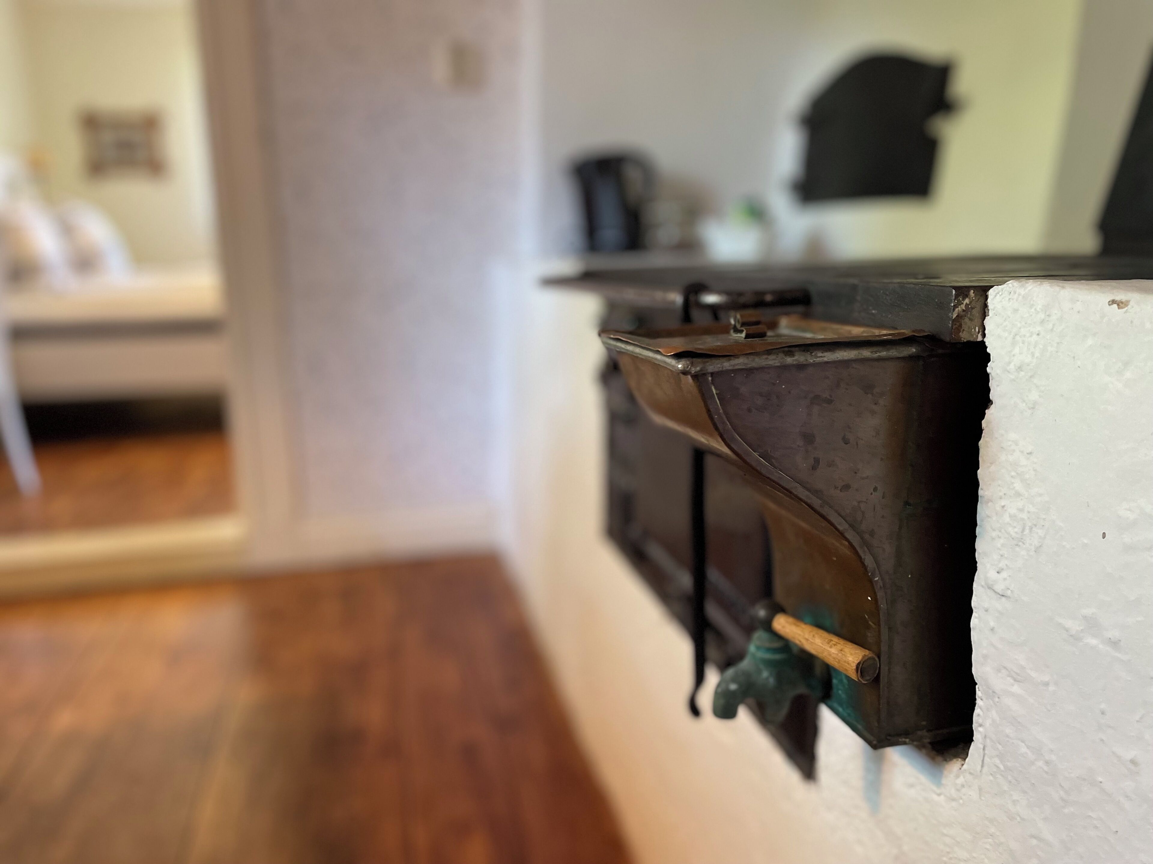 A close-up of a kitchen corner with a wooden countertop, a metal appliance, and a green faucet.