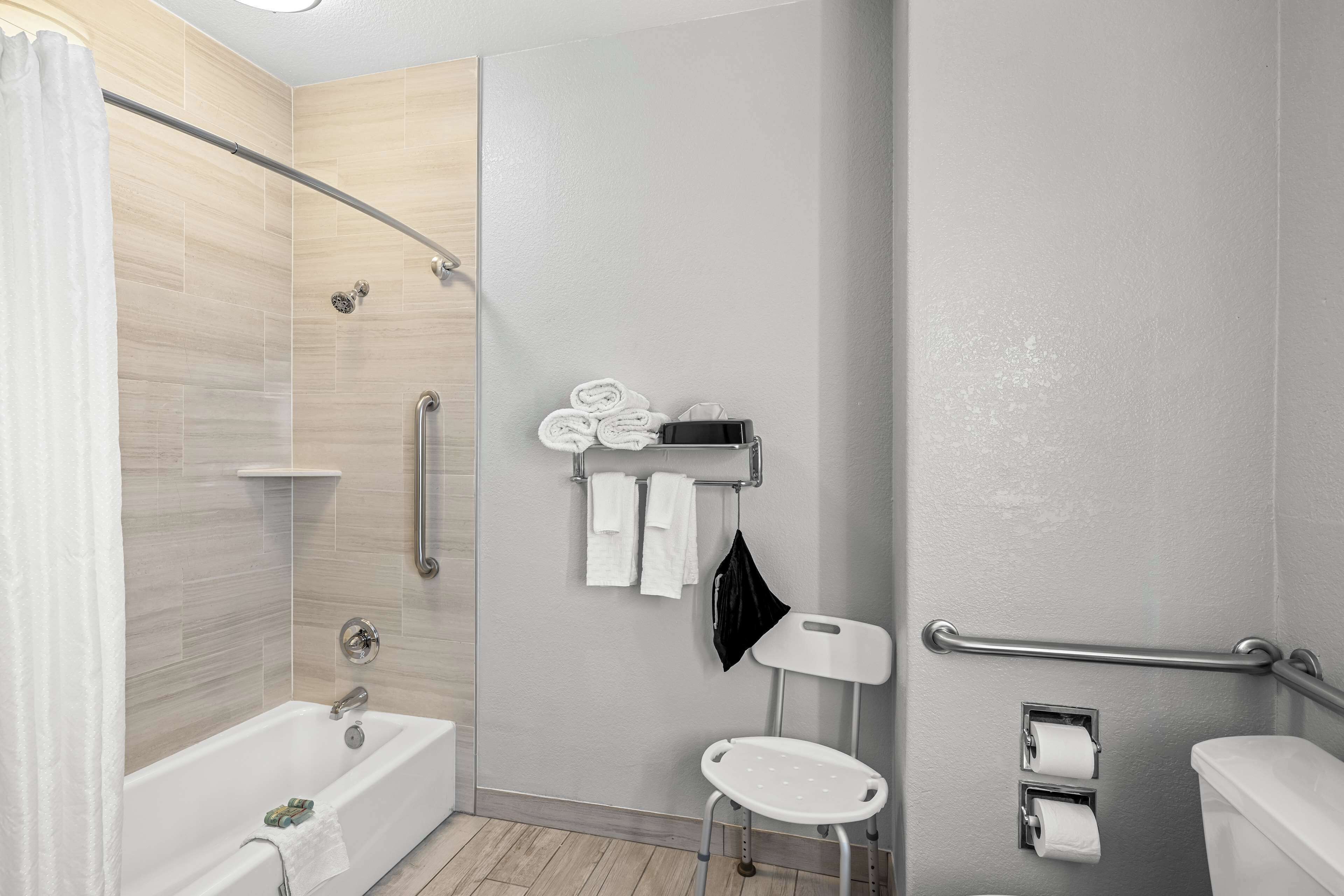 Un baño moderno con bañera, ducha, inodoro y barra de apoyo.