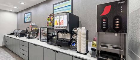 Eine moderne Kaffee-Station mit mehreren Getränkeausgaben, darunter eine Nescafé-Maschine, und einer Auswahl an Kaffeekapseln.