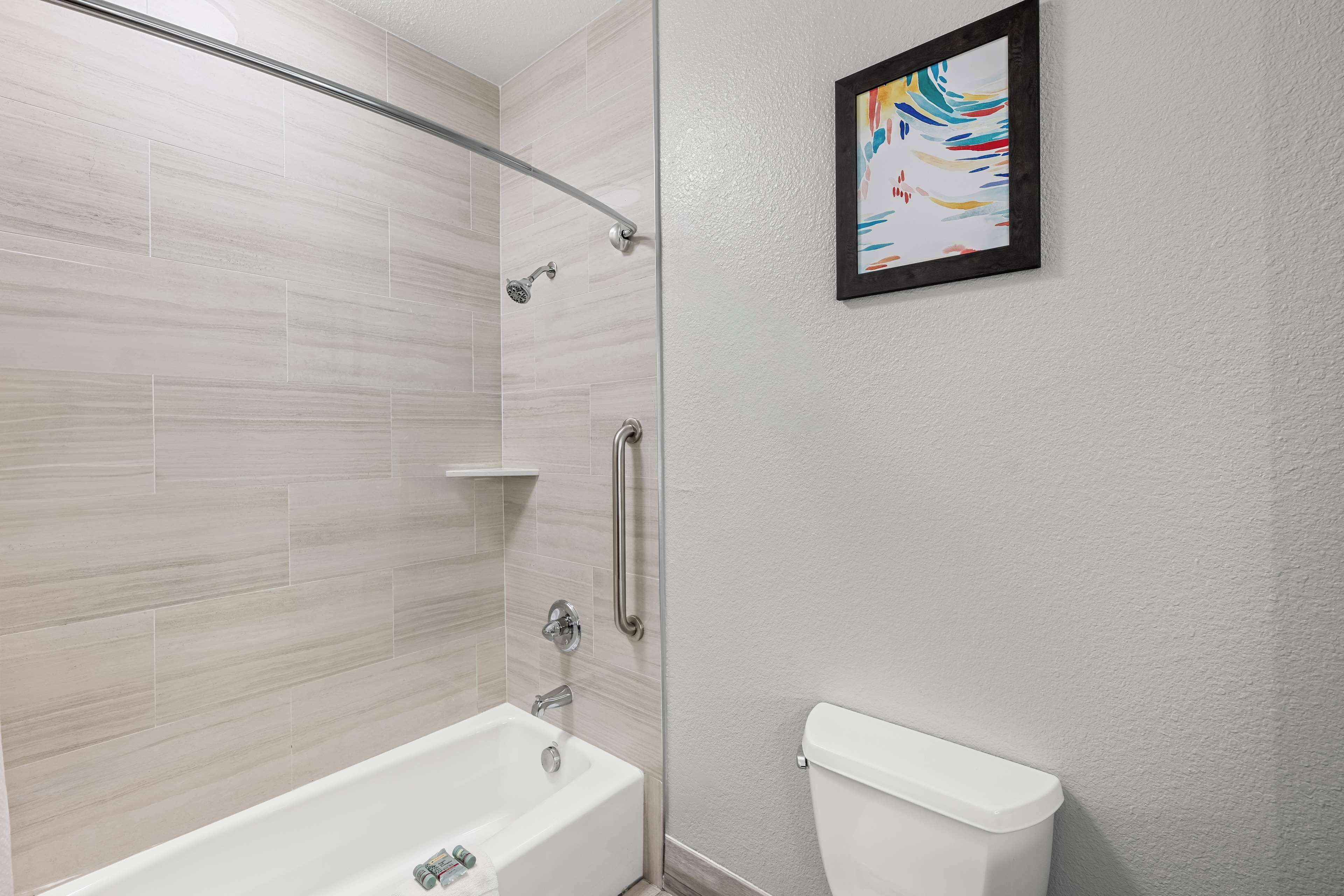 Une salle de bain moderne avec une douche à parois de verre, une baignoire blanche et des toilettes.