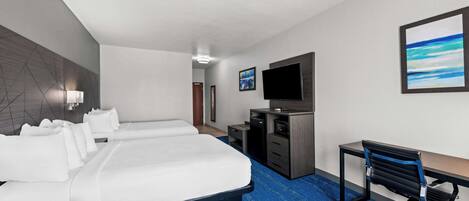 Habitación de hotel con una cama grande, un escritorio con silla, televisión y obras de arte en las paredes.