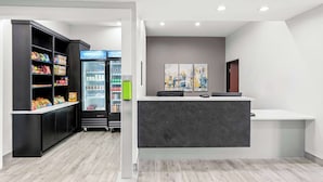 A reception area with a counter, a refrigerator stocked with beverages, and shelves with snacks.