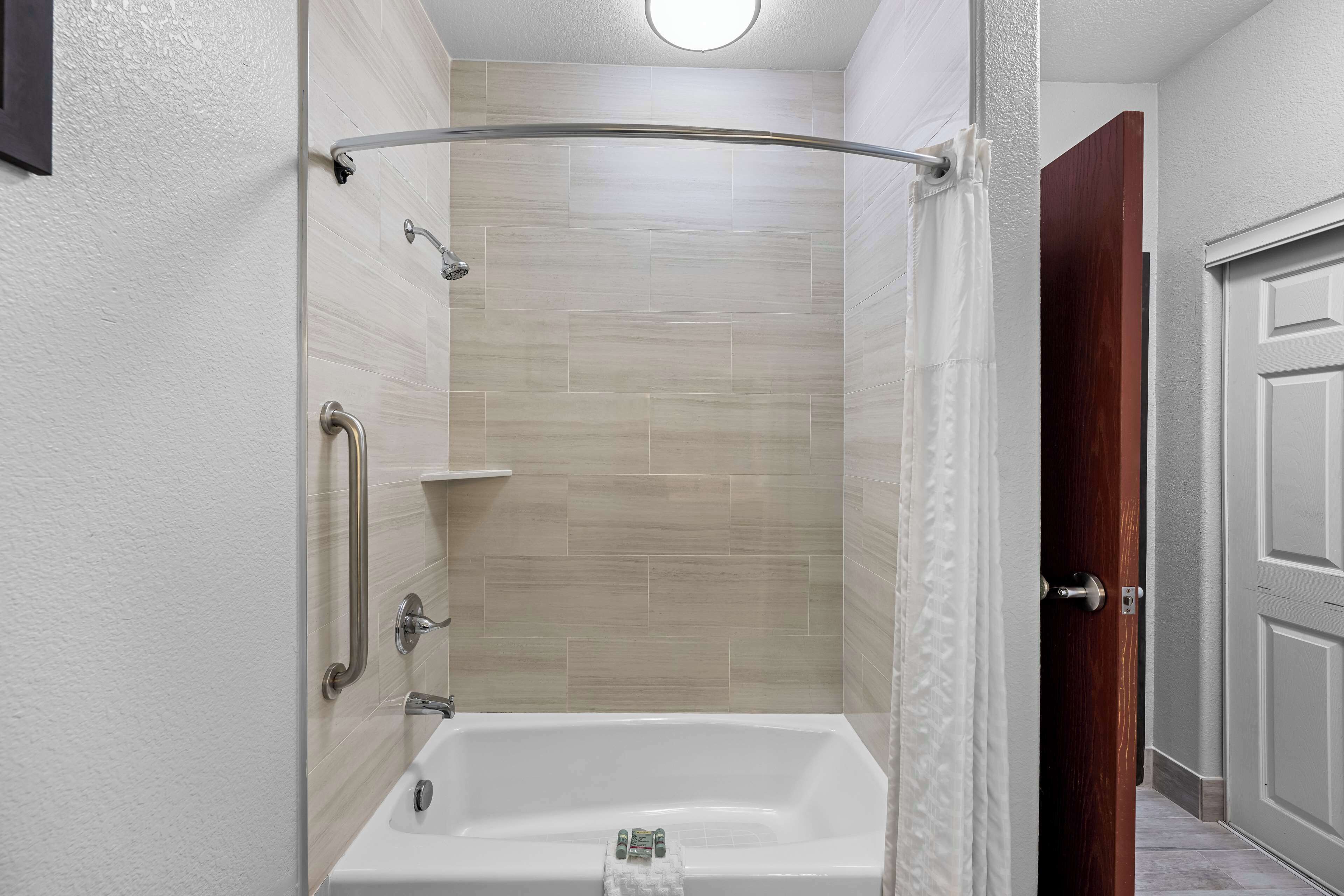 A bathroom with a bathtub, a shower, and a door.