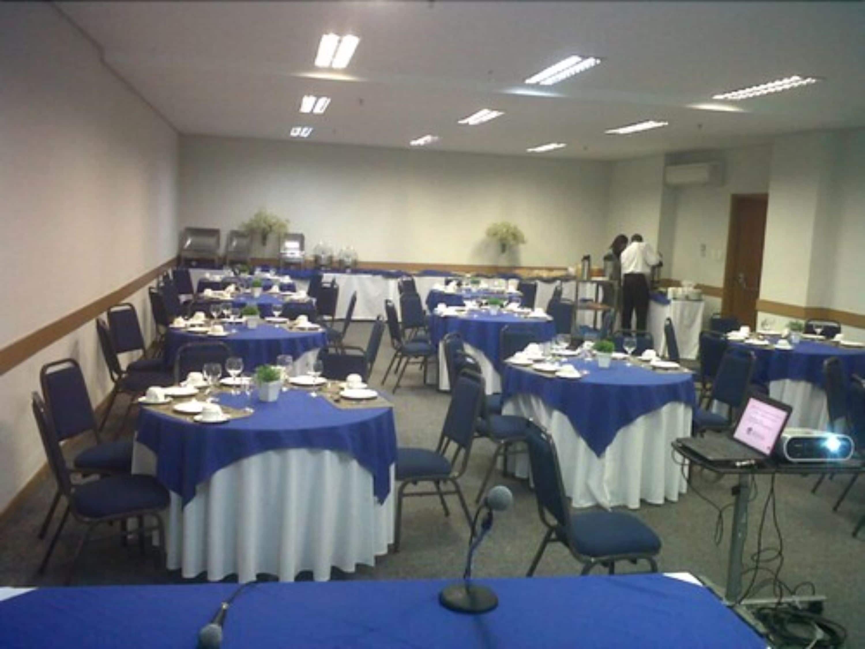 A conference room with round tables, chairs, and a podium.