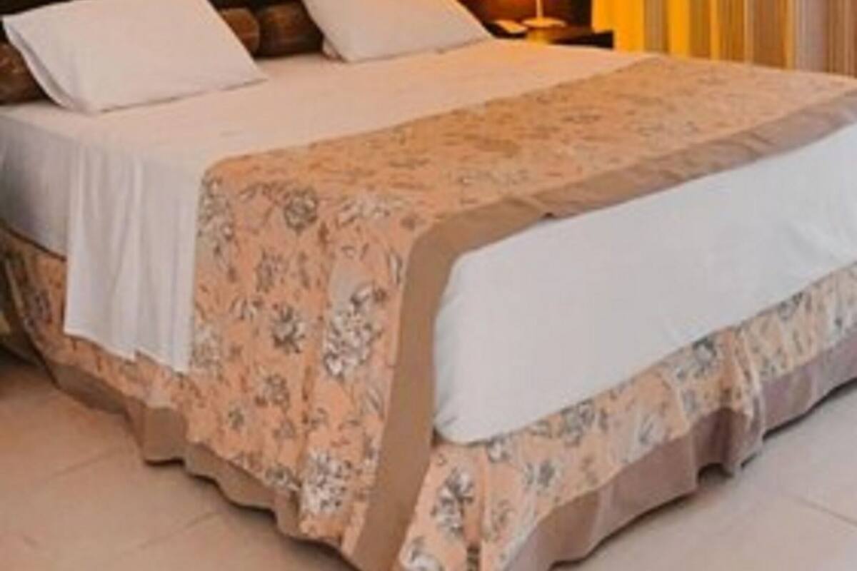 Una camera d'albergo con un letto, un comodino, una lampada e un quadro appeso al muro.