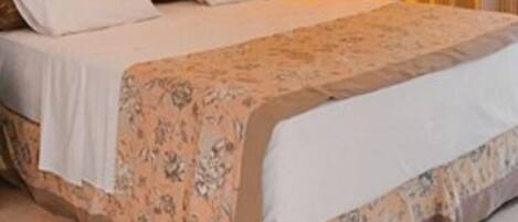 A hotel room with a bed, a nightstand, a lamp, and a painting on the wall.
