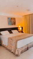 Una camera d'albergo con un letto, un comodino, una lampada e un quadro appeso al muro.