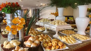 A buffet with various baked goods and flowers. - América Towers Hotel (Salvador)