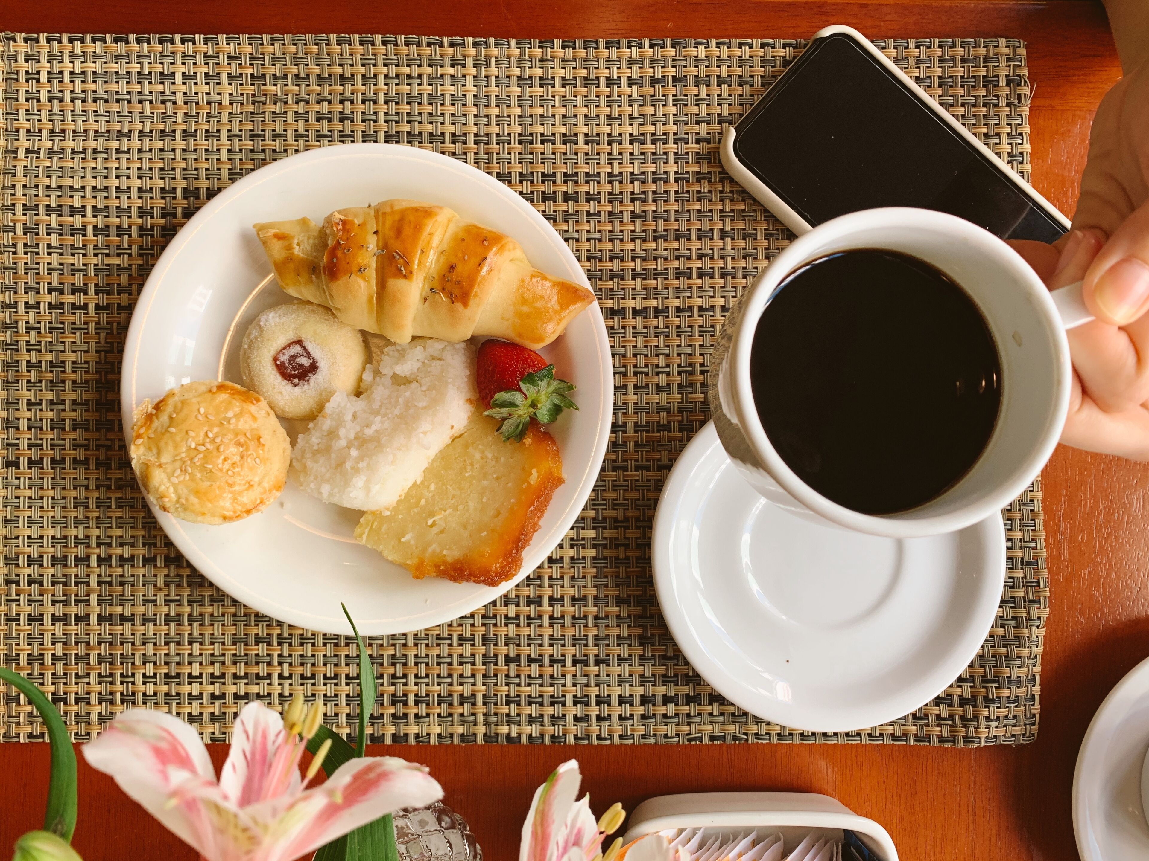 A plate of food with a cup of coffee on a woven placemat.