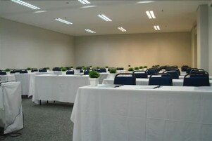 A conference room with multiple tables, chairs, and potted plants.