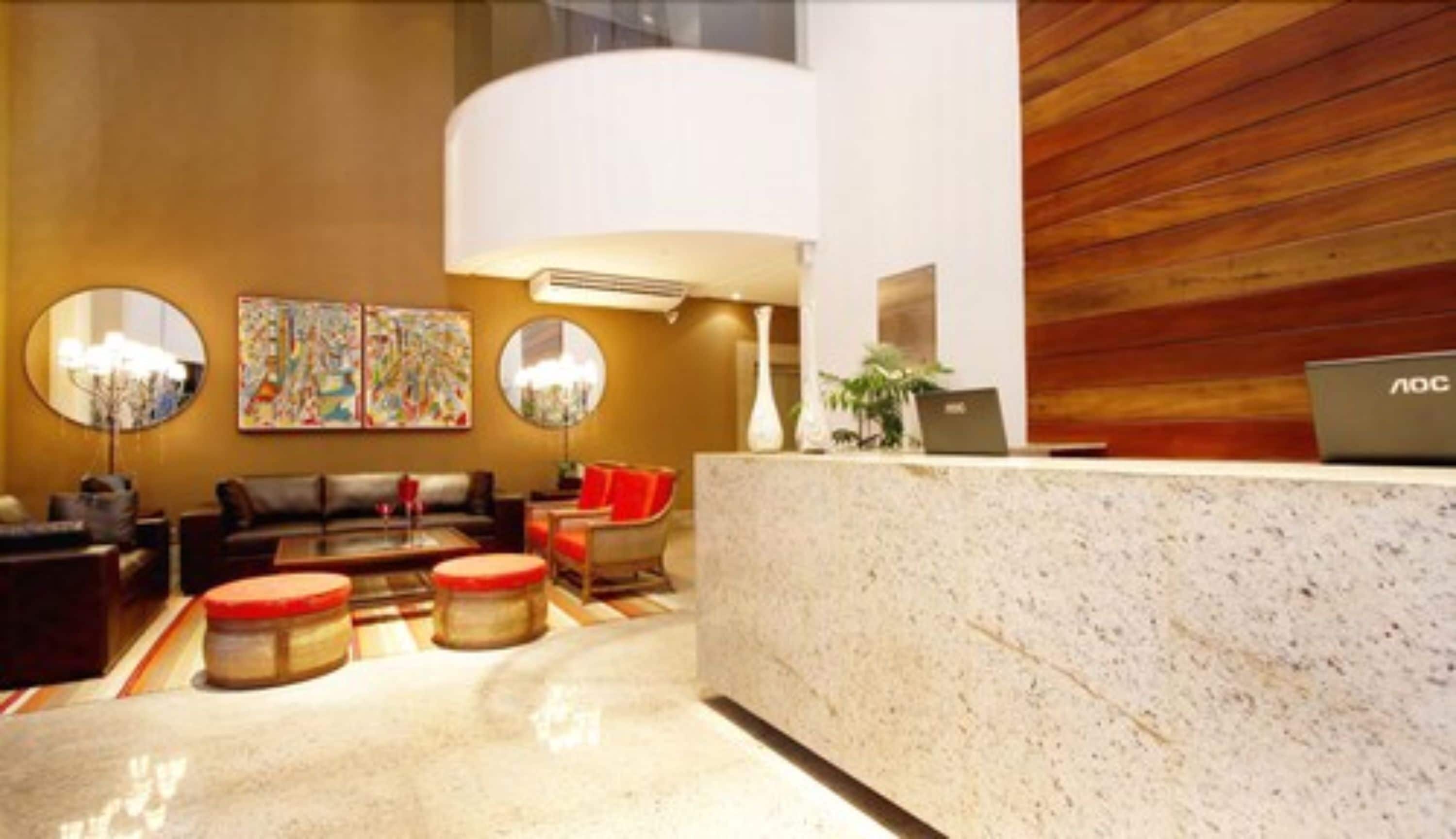 A lobby with a reception desk, a sofa, a coffee table, and two round mirrors.