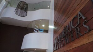 A modern interior with a wooden wall and a sign reading "AMERICA MOTHERS". - América Towers Hotel (Salvador)
