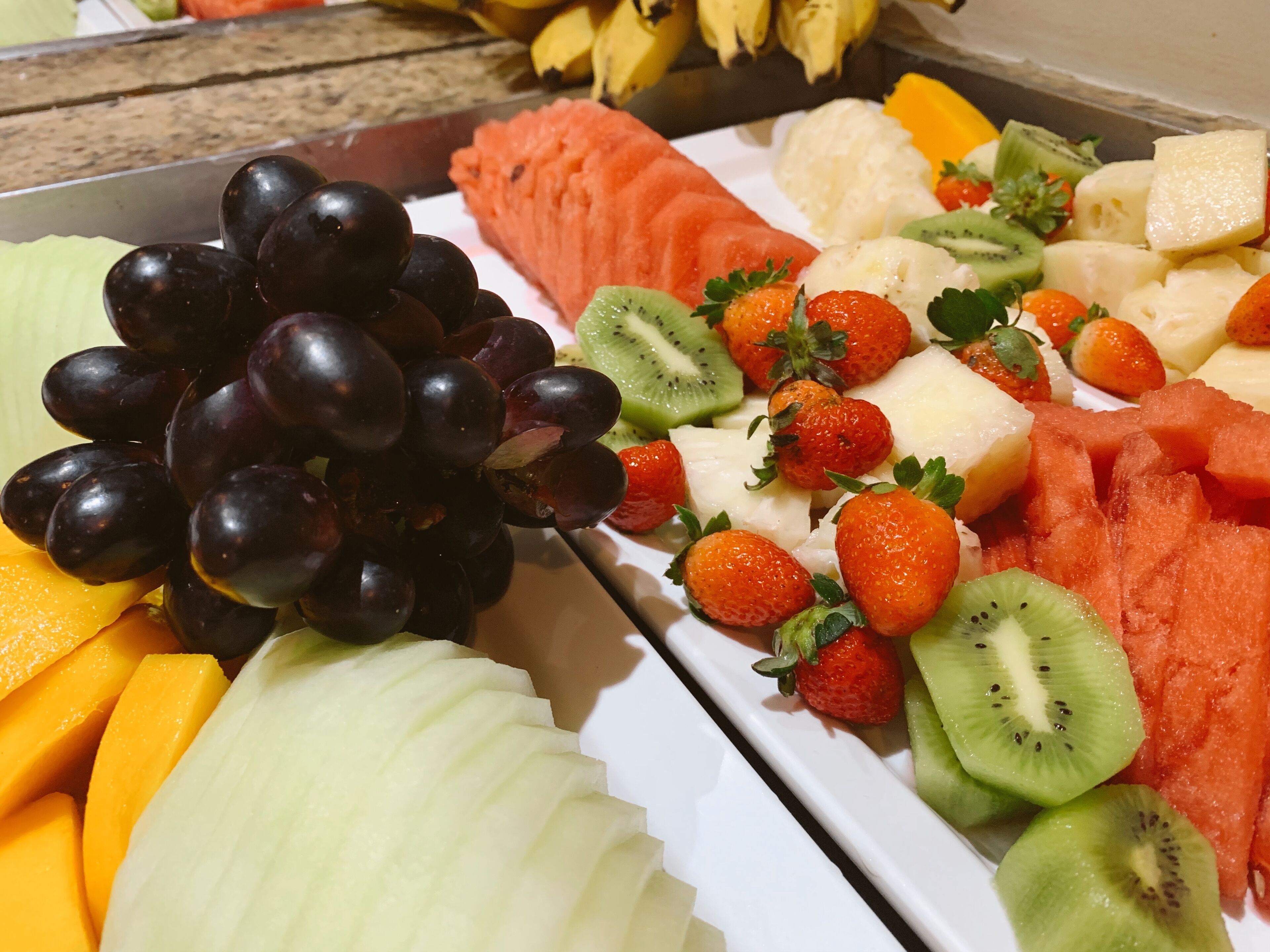 Eine Obstplatte mit Trauben, Erdbeeren, Kiwis, Wassermelone und Ananas.