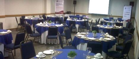 A conference room with multiple tables set for a meeting, equipped with chairs, tables, and presentation screens.