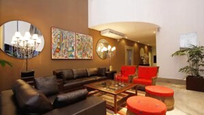 A modern living room with a leather sofa, a glass coffee table, and red accent chairs. - América Towers Hotel (Salvador)