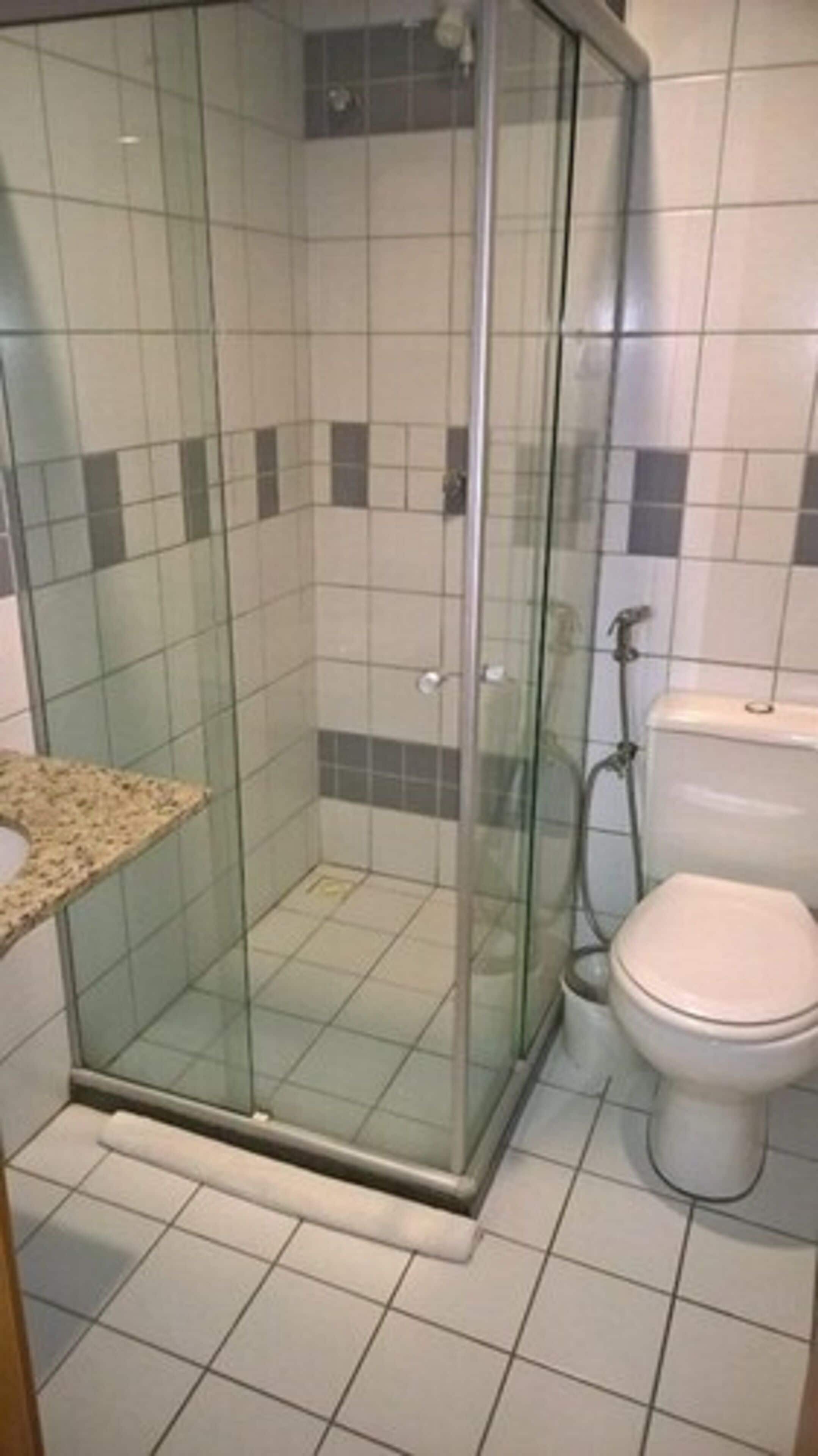 A bathroom with a glass-enclosed shower, a toilet, and a tiled floor.