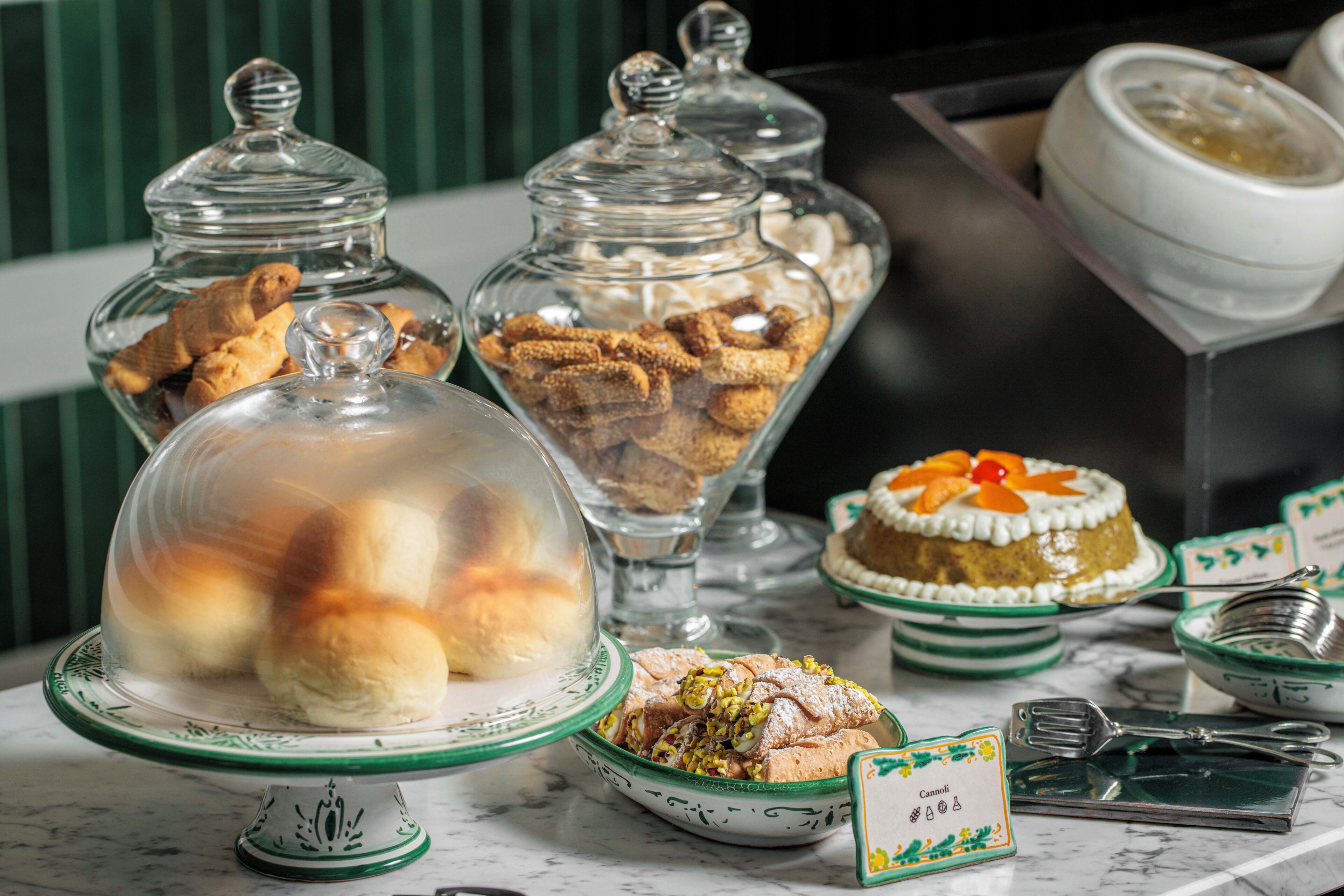 A variety of desserts displayed on a marble countertop with glass containers and serving dishes.
