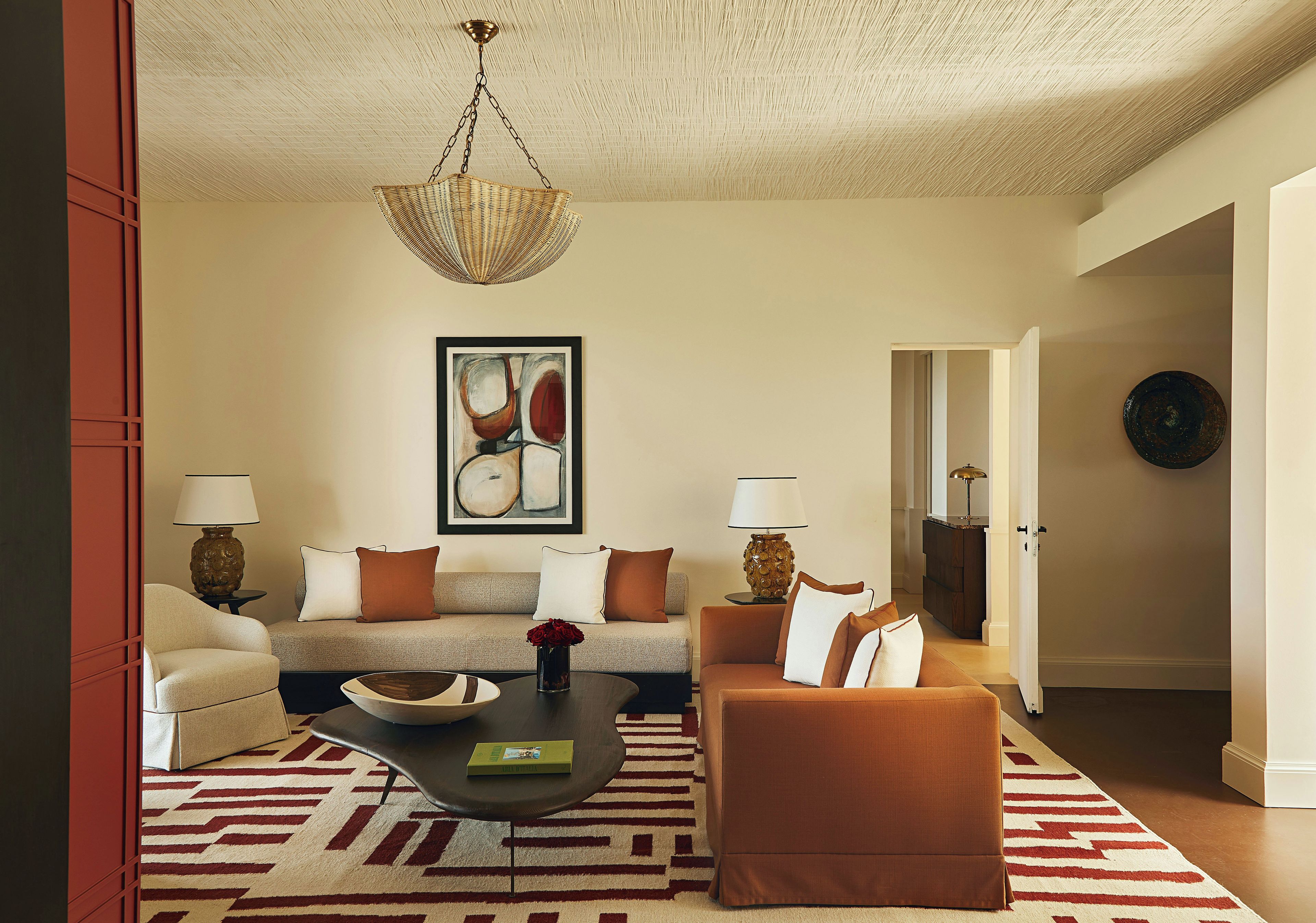 A living room with a sofa, armchairs, a coffee table, and a hanging light fixture.