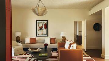 A living room with a sofa, armchairs, a coffee table, and a hanging light fixture.