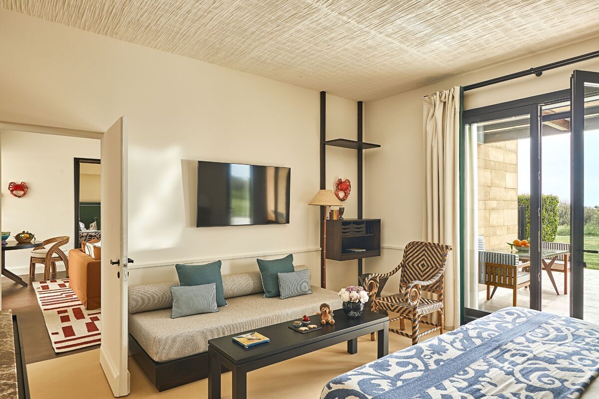 Une chambre d’hôtel moderne dotée d’un canapé, d’une télévision, d’un coin repas et d’un balcon.
