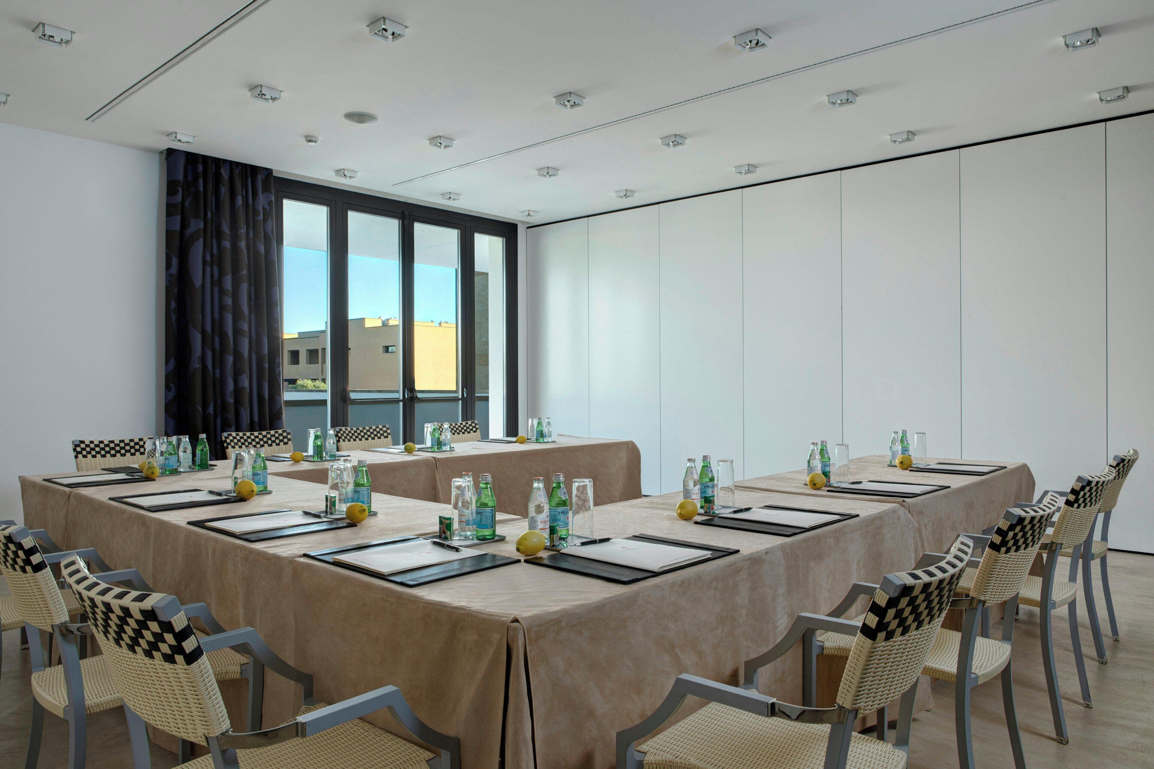 A conference room with a large table, chairs, and a view of buildings outside.
