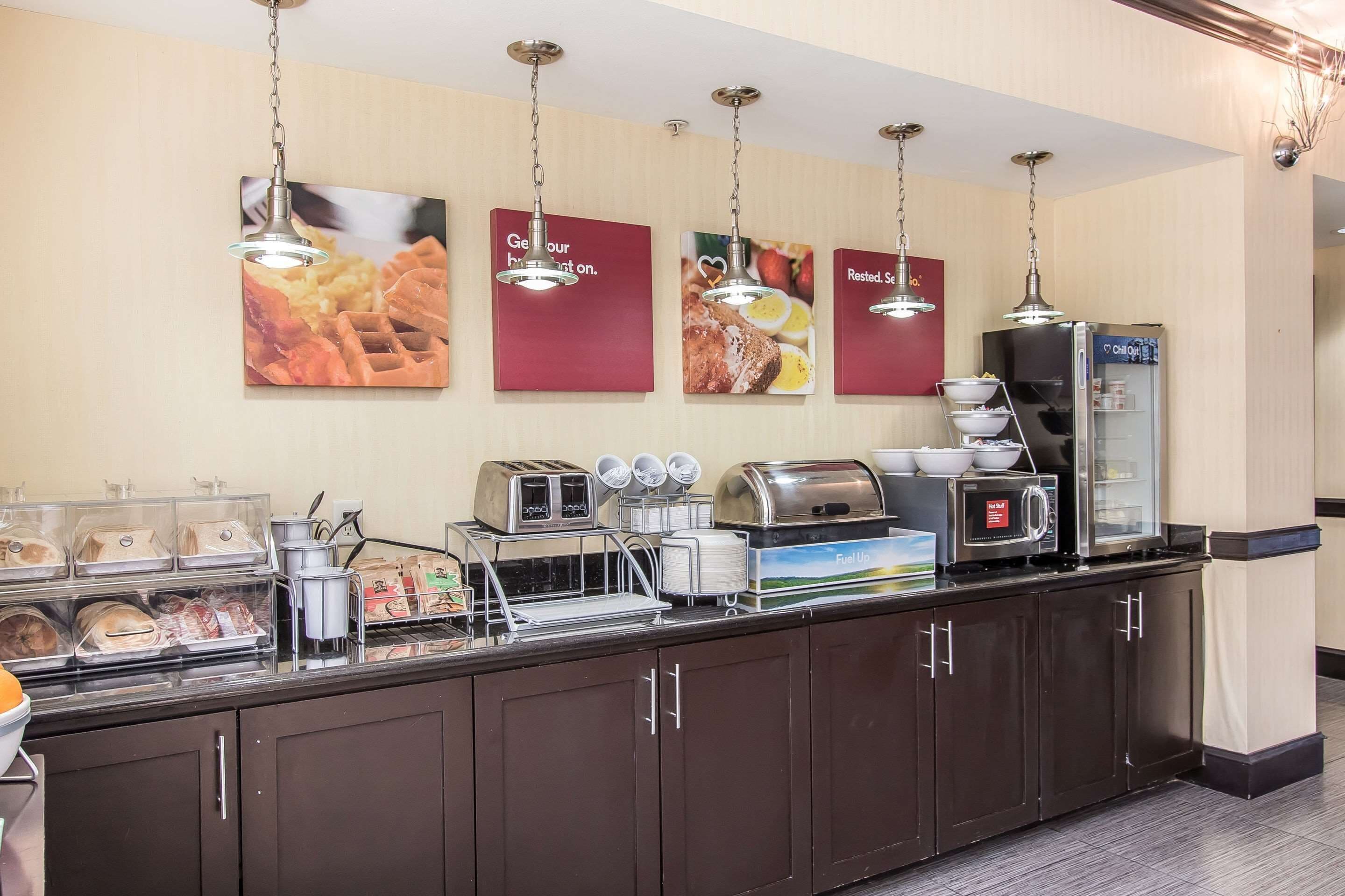 A breakfast bar with a coffee machine, toaster, and food display.
