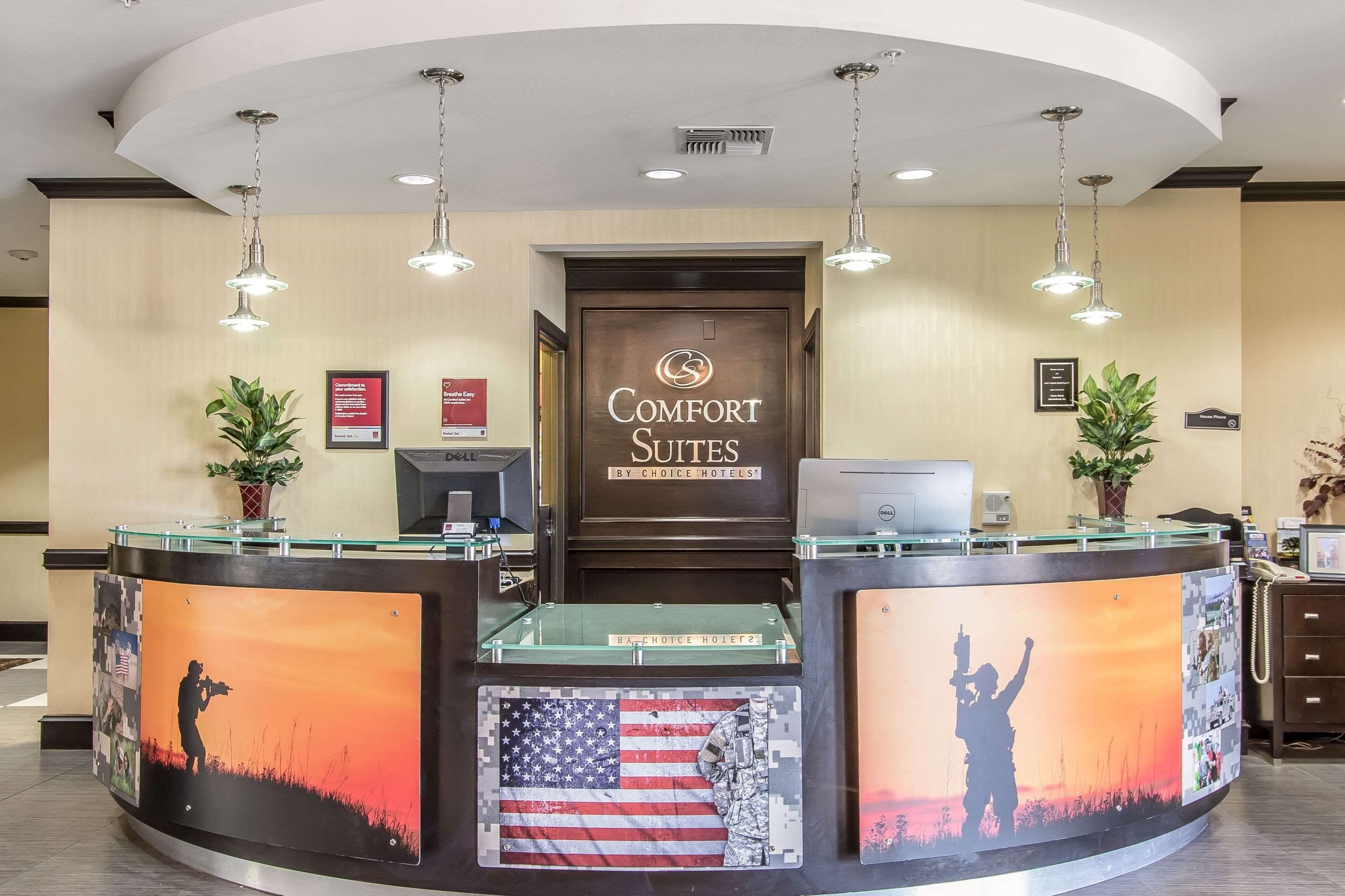 A reception desk with a sign reading "Comfort Suites by Choice Hotels," featuring a large American flag and a soldier silhouette.