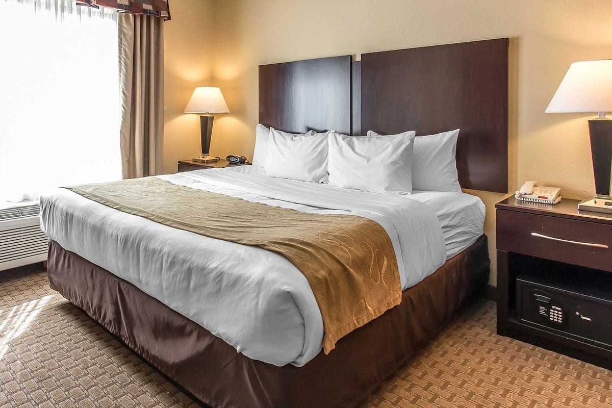 Habitación de hotel con una cama grande, dos mesitas de noche, una lámpara y un teléfono.
