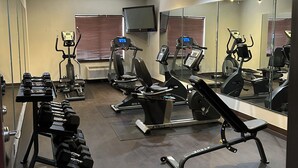 Un gimnasio con cintas de correr, elípticas y pesas sueltas.