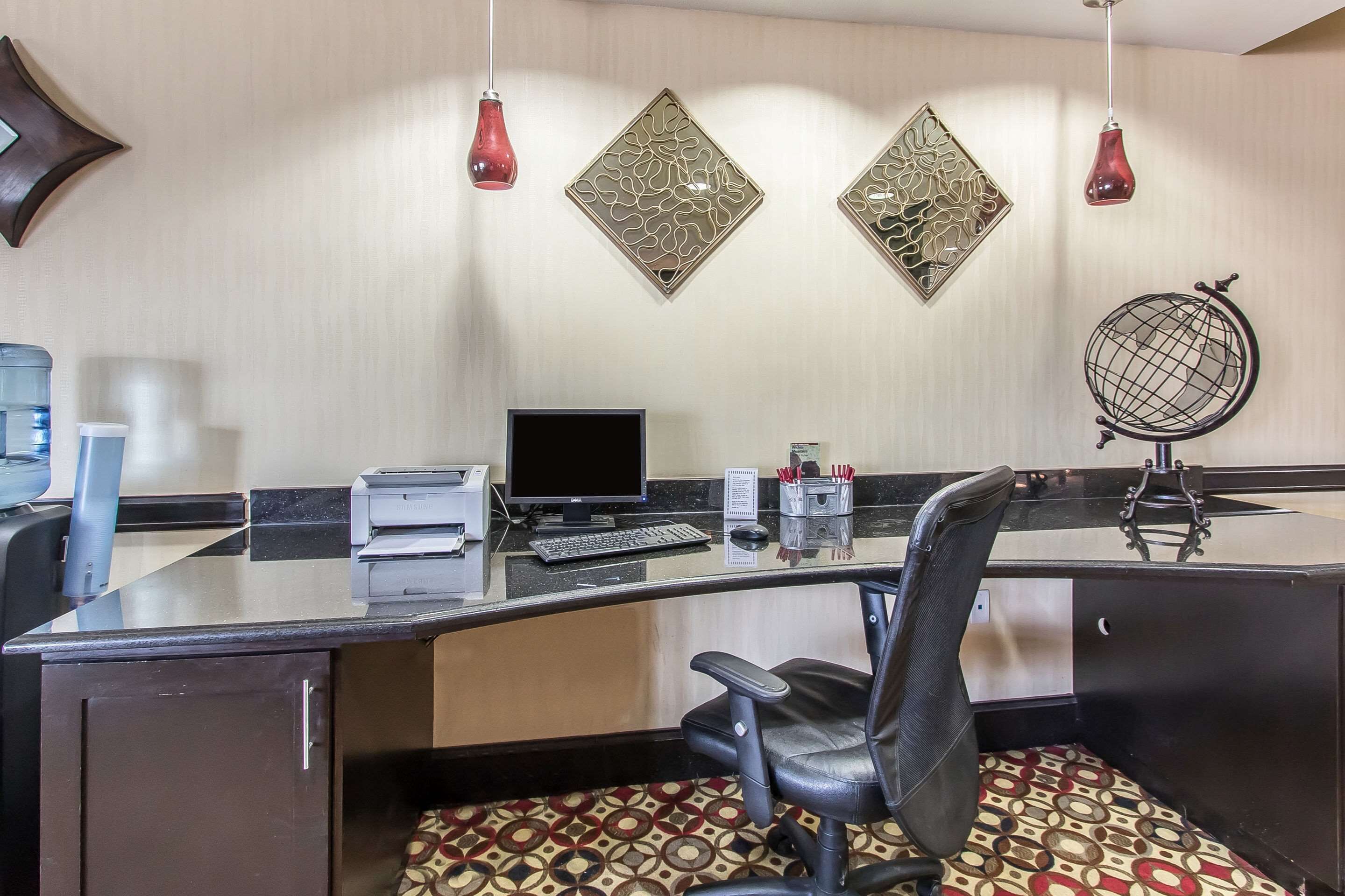 Un mostrador de recepción de hotel con computadora, impresora y lámpara de escritorio.