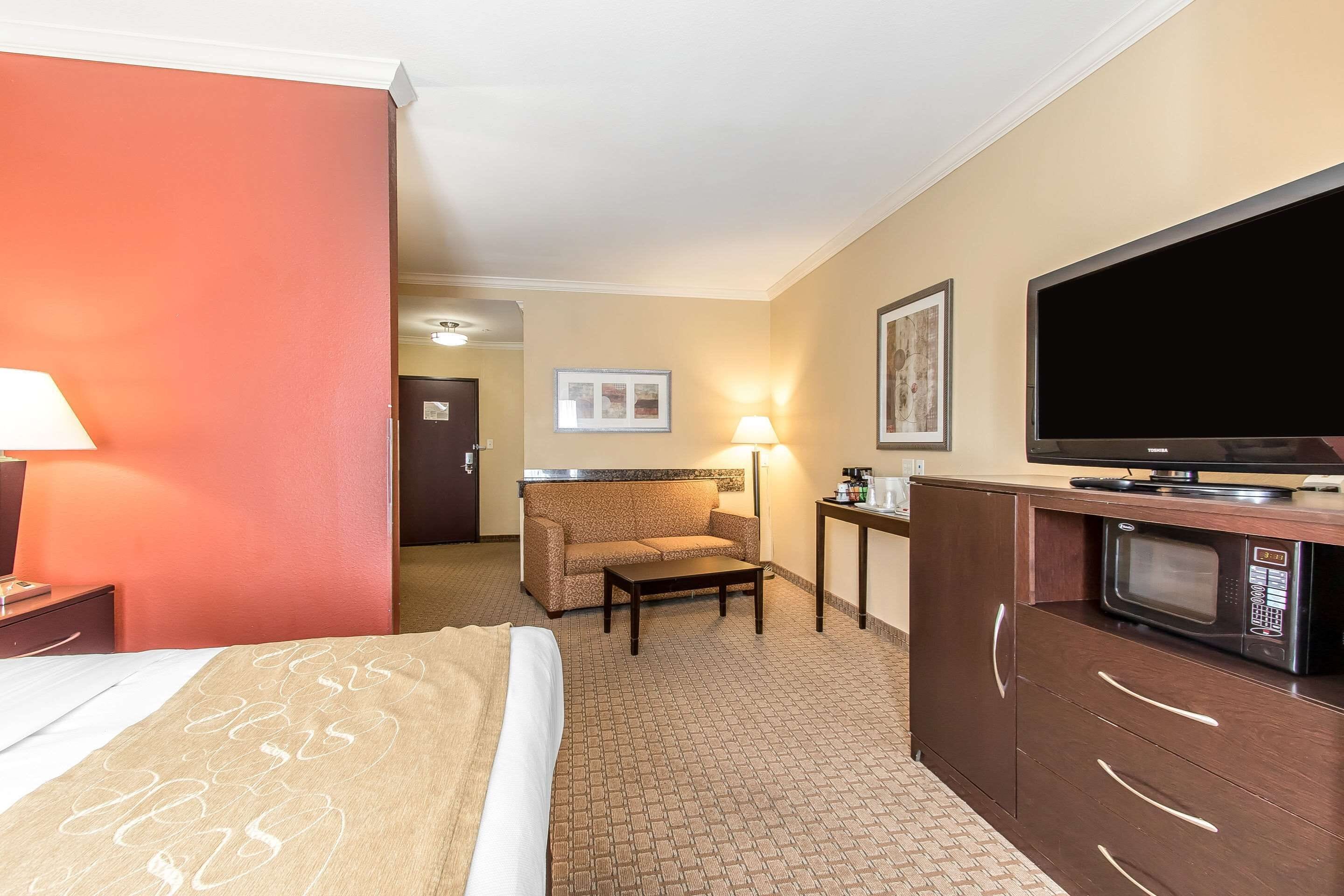 Een hotelkamer met een bed, een bank, een televisie, een magnetron en een klein tafeltje.