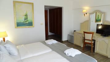 Ein Hotelzimmer mit Bett, Schreibtisch, Sessel, Fernseher und einem Bild an der Wand.