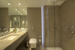 A modern bathroom with a large mirror, a sink, a toilet, and a glass-enclosed shower area.