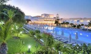 A hotel with a large pool, sun loungers, and a well-lit outdoor dining area. - Hotel Platanista (Kos)