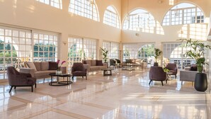 A spacious lobby with high ceilings, large arched windows, and a polished tile floor. - Hotel Platanista (Kos)