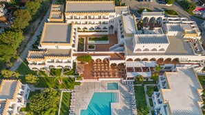 An aerial view of a resort with a central swimming pool, multiple guest rooms, and outdoor seating areas. - Hotel Platanista (Kos)