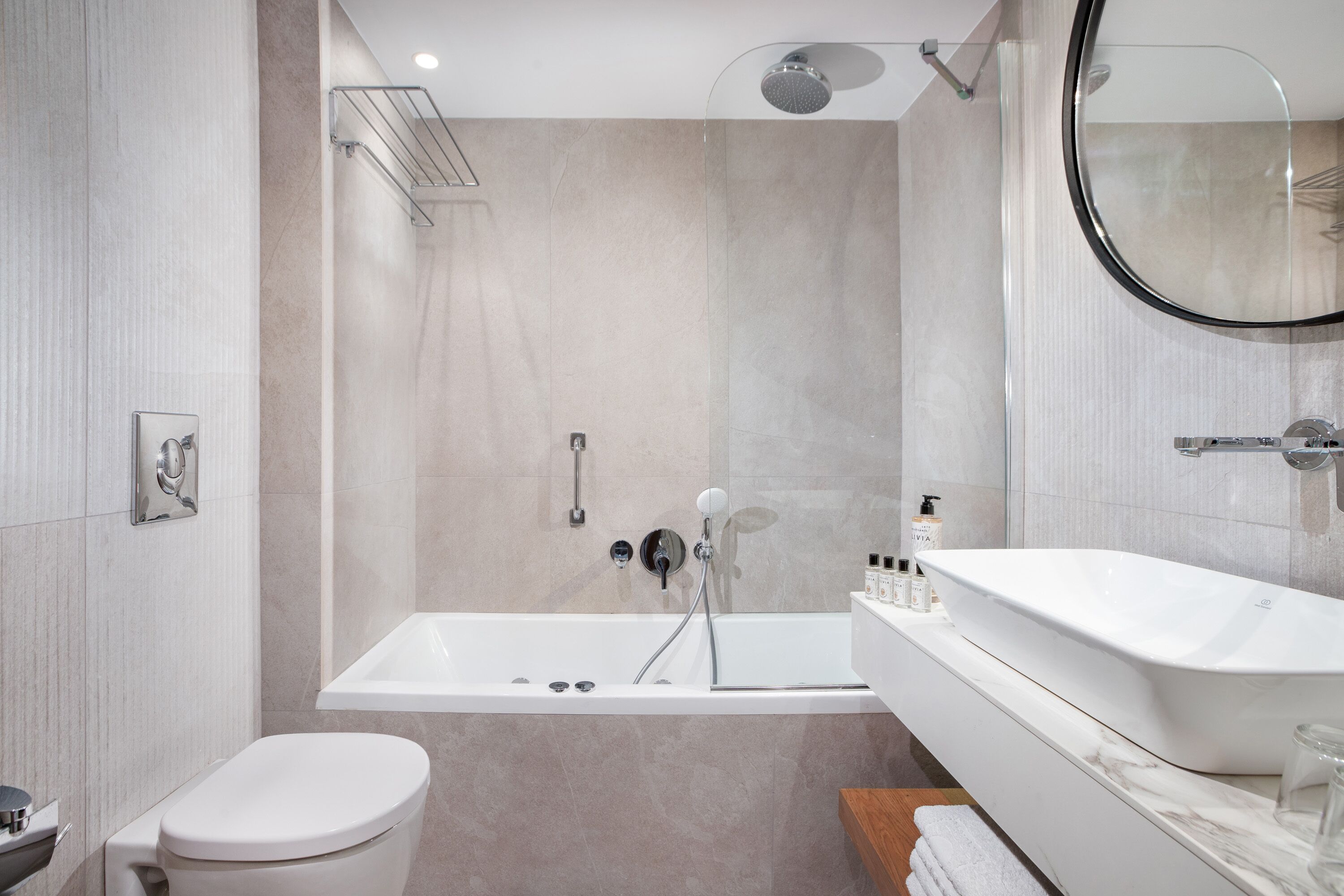 A modern bathroom with a bathtub, toilet, and a large mirror.