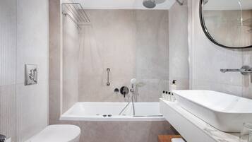 A modern bathroom with a bathtub, toilet, and a large mirror.