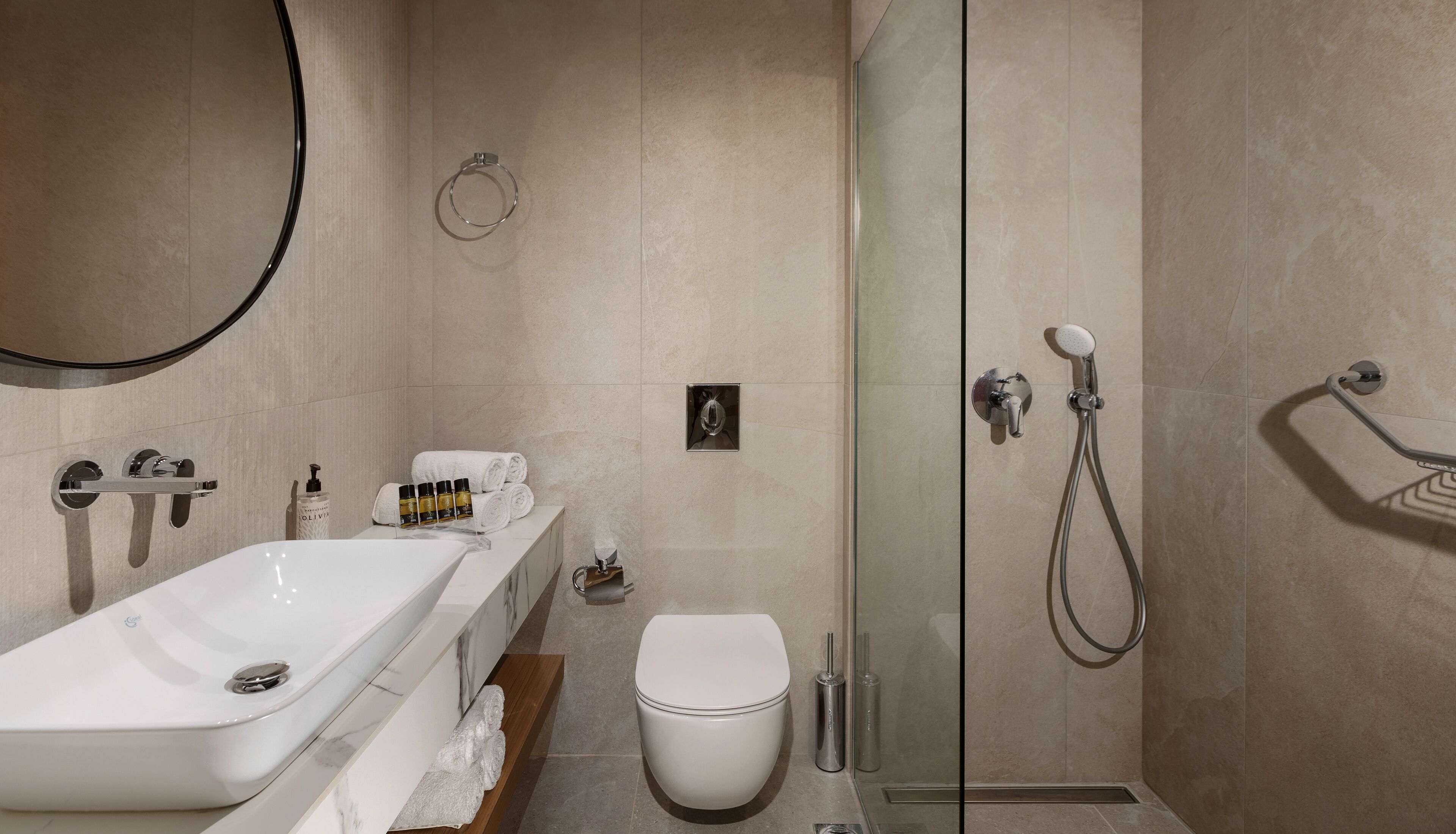Un baño moderno con lavamanos, inodoro y ducha blancos.