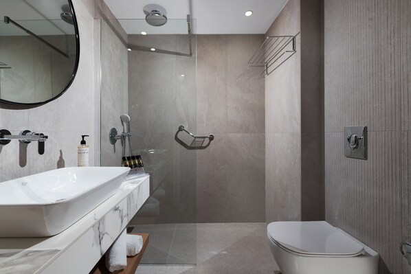 A modern bathroom with a large white sink, a toilet, and a glass-enclosed shower area.