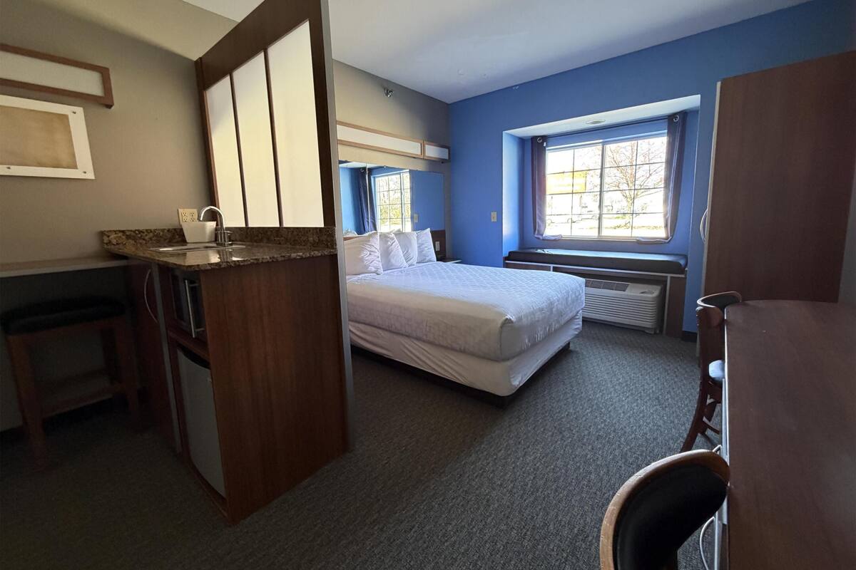 Une pièce comprenant un lit, un bureau, un lavabo et une fenêtre.