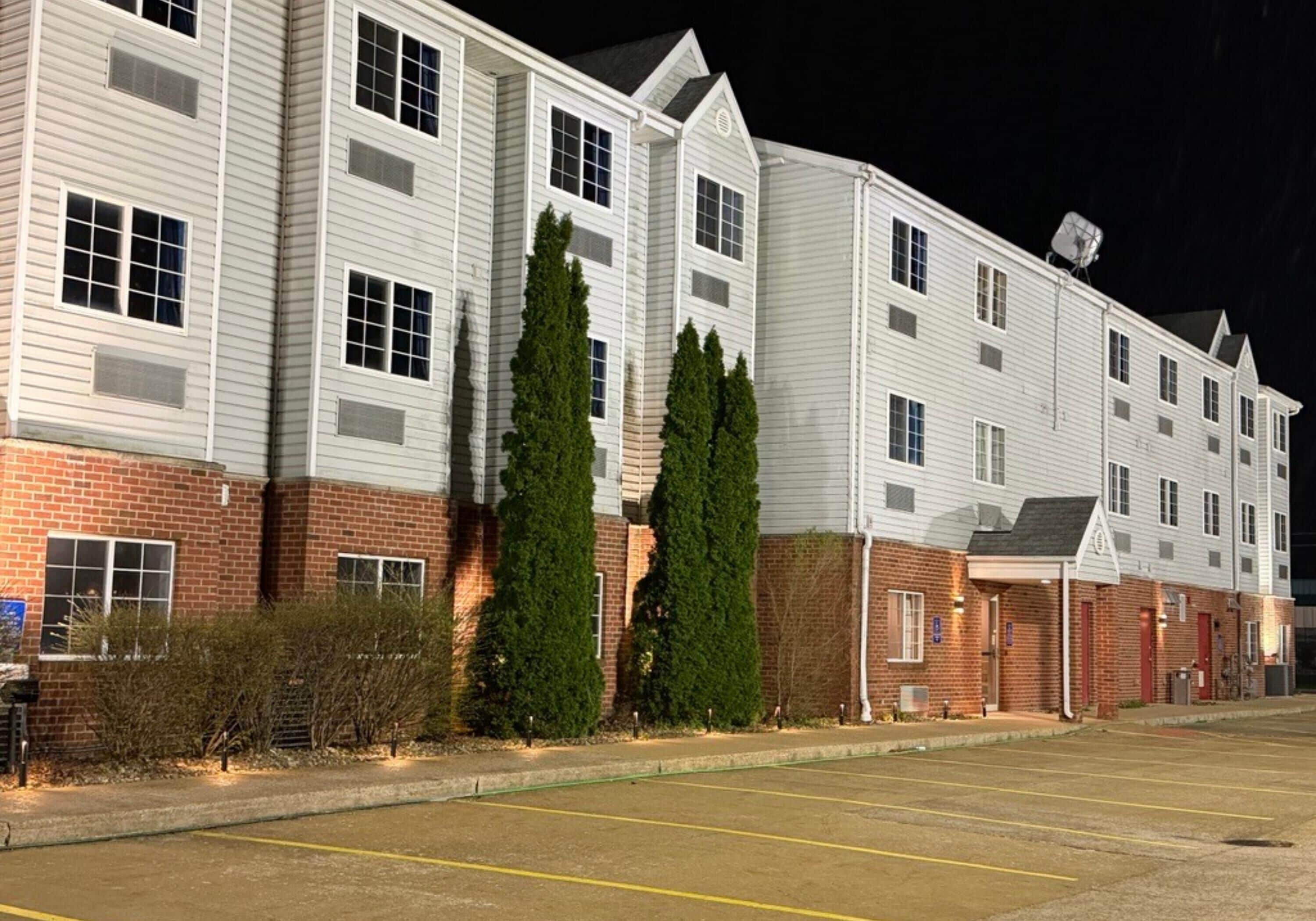 A multi-story hotel with a brick facade, large windows, and a parking lot.